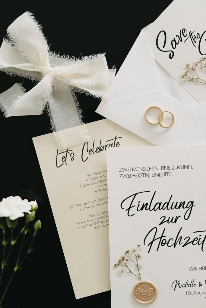 Flatlay einer Hochzeitspapeterie von Fancy Design in dezenten Cremetönen mit Chiffonband & Wachssiegel