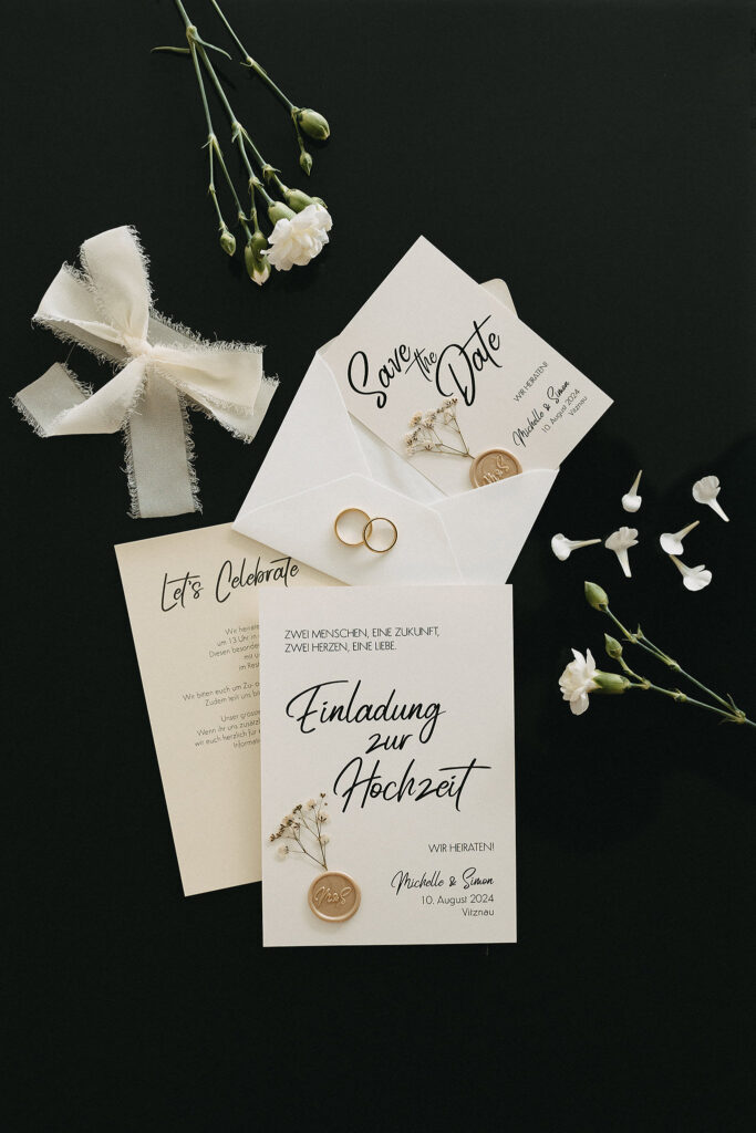Flatlay einer Hochzeitseinladung & Save the Date von Fancy Design in dezenten Cremetönen mit Chiffonband & Wachssiegel