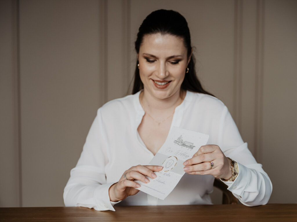 Designerin für Hochzeitspapeterie mit Einladung in der Hand die ein individuelles Hochzeitslogo hat