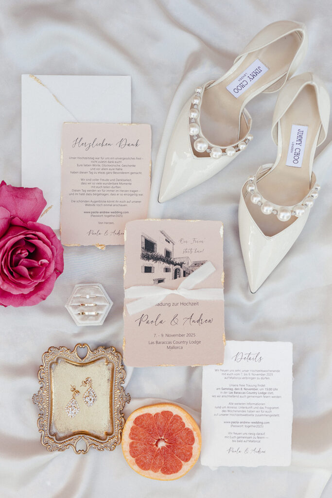 Flatlay von einem luxuriösen Einladungsset für eine Hochzeit auf Mallorca auf handgeschöpftem Papier mit Blattgold, Location Illustration und Seidenband